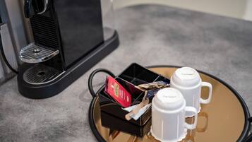 A coffee machine with a tray containing two white cups and a box of coffee pods.