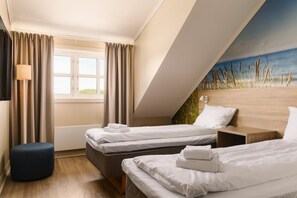 A hotel room with two beds, a window with curtains, a lamp, and a painting on the wall.