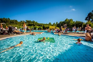 A swimming pool with people swimming and lounging around.
