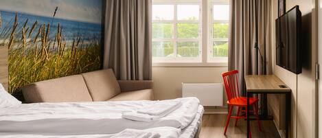 A hotel room with a bed, a desk, a chair, a TV, and a window with curtains.