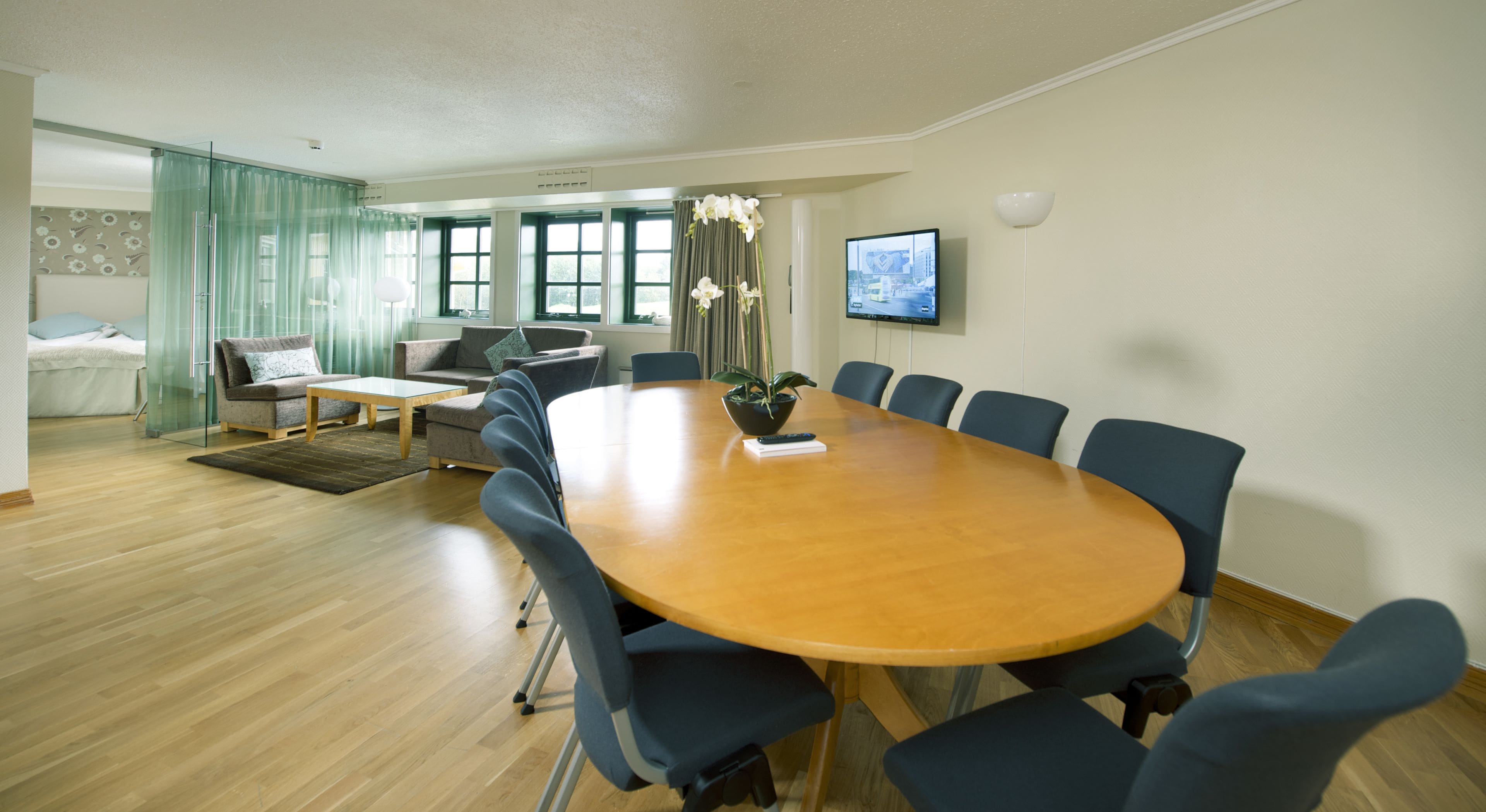 Un salón de conferencias con una gran mesa de madera, sillas azules y una planta en maceta.