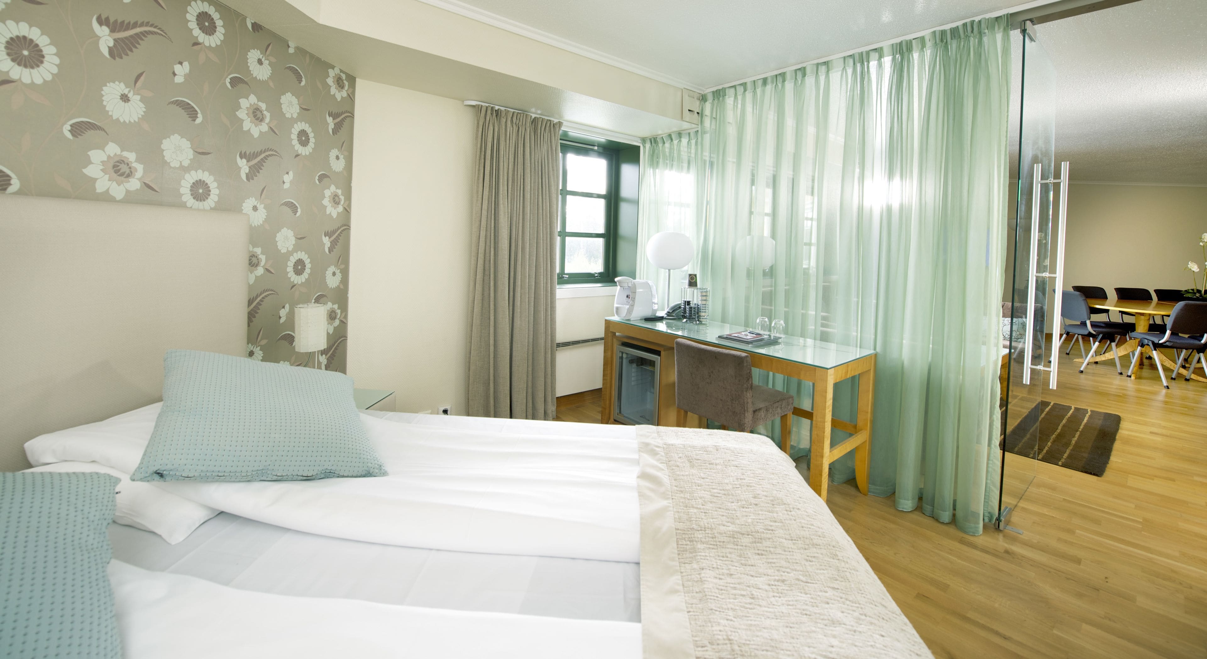 Habitación de hotel con una cama grande, un escritorio y un comedor con sillas.