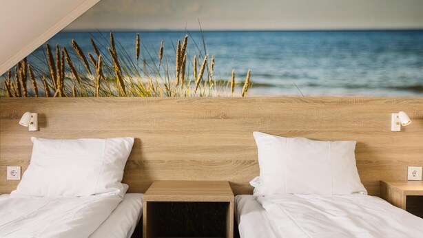 Un dormitorio con dos camas, cabeceros de madera y vistas al océano.