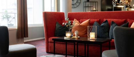 A modern living room with a red sofa, black and grey chairs, a black coffee table, and a patterned carpet.