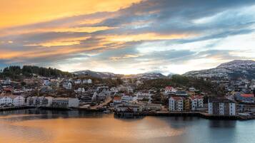 A coastal town with buildings along the waterfront, a dock, and a mountainous backdrop.