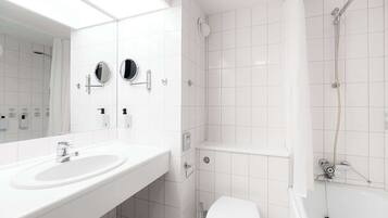 A modern bathroom with a white sink, two mirrors, a toilet, and a shower.