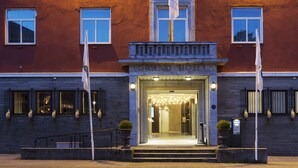 A hotel entrance with a stone facade, a grand entrance, and a flagpole. - Quality Hotel Grand Kristiansund (Kristiansund)
