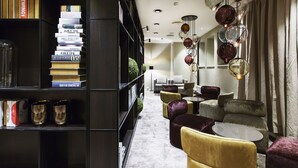 A modern library with bookshelves, a seating area with round tables, and decorative hanging lights. - Quality Hotel Grand Kristiansund (Kristiansund)