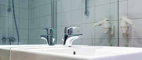 A modern bathroom with a large mirror, a white sink, and a shower area.