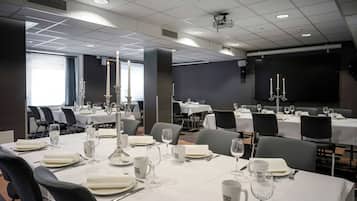A conference room with tables set for a meeting, equipped with projectors and screens.