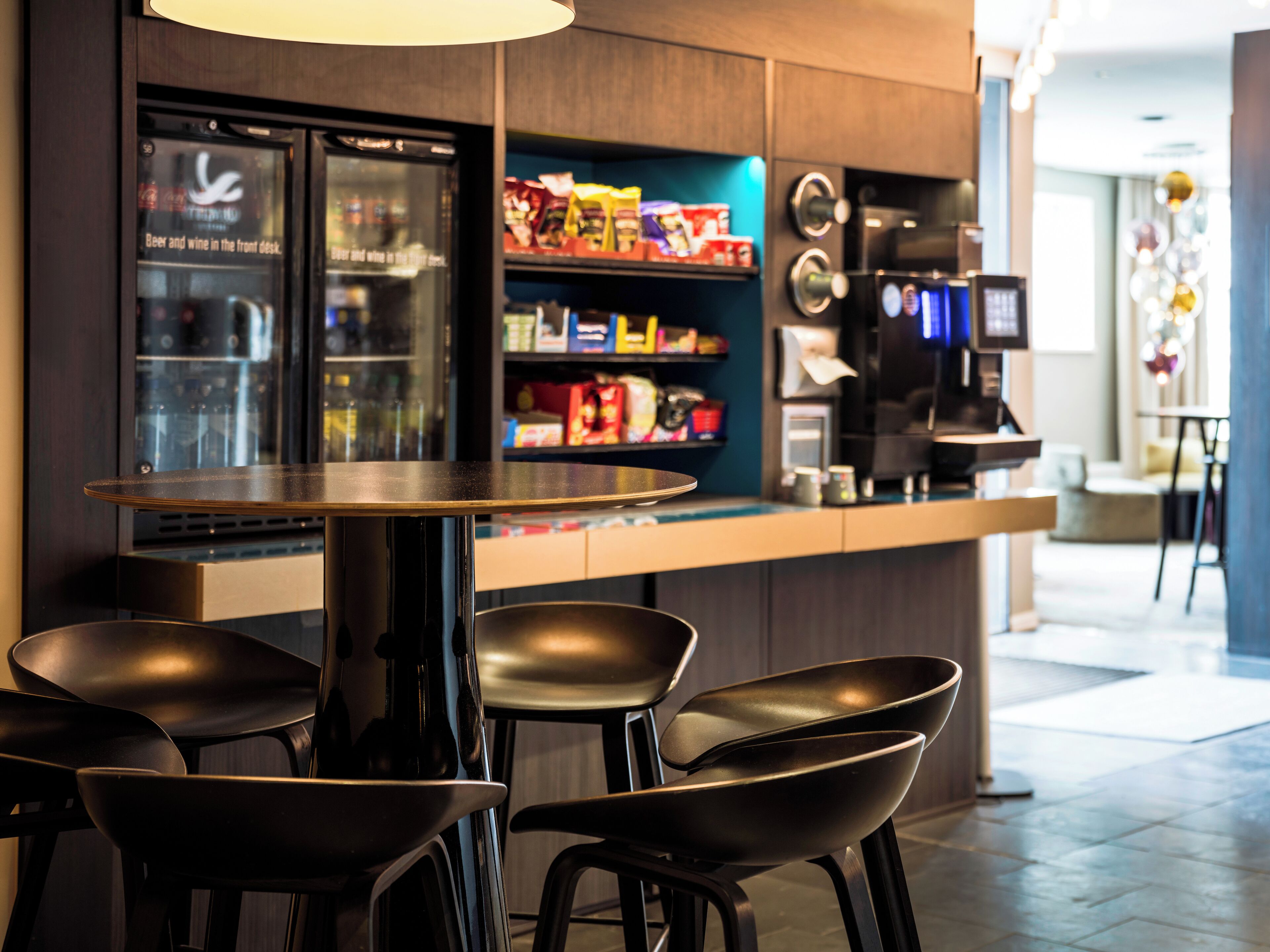Un área de bar moderna con mostrador, asientos y refrigerador.