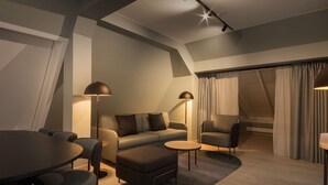 Una sala moderna con sofá, reposapiés, mesa de centro redonda y sillones.