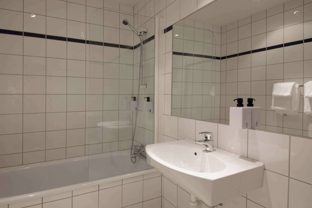 A modern bathroom with a glass-enclosed shower, a white sink, and a large mirror.
