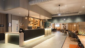 Un moderno vestíbulo de hotel con mostrador de recepción, zona de estar y bar.