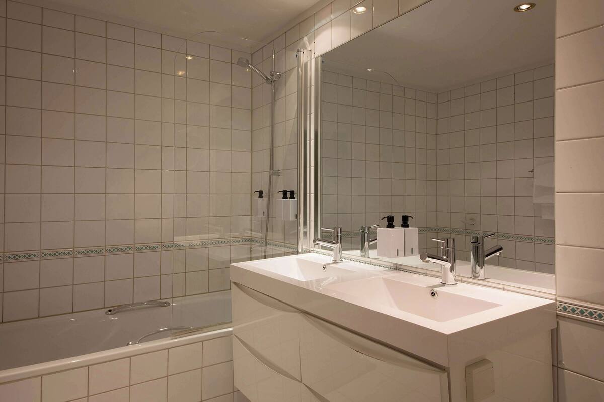 A modern bathroom with two sinks, a large mirror, and a shower enclosure.