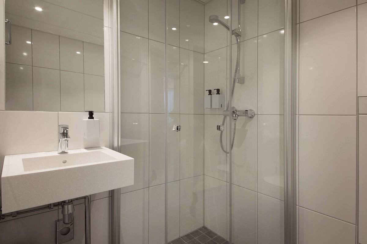 A modern bathroom with a white sink, a glass shower enclosure, and a mirror.