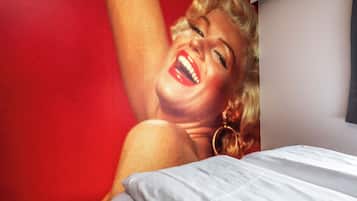 A bed with white bedding and a red wall in the background.