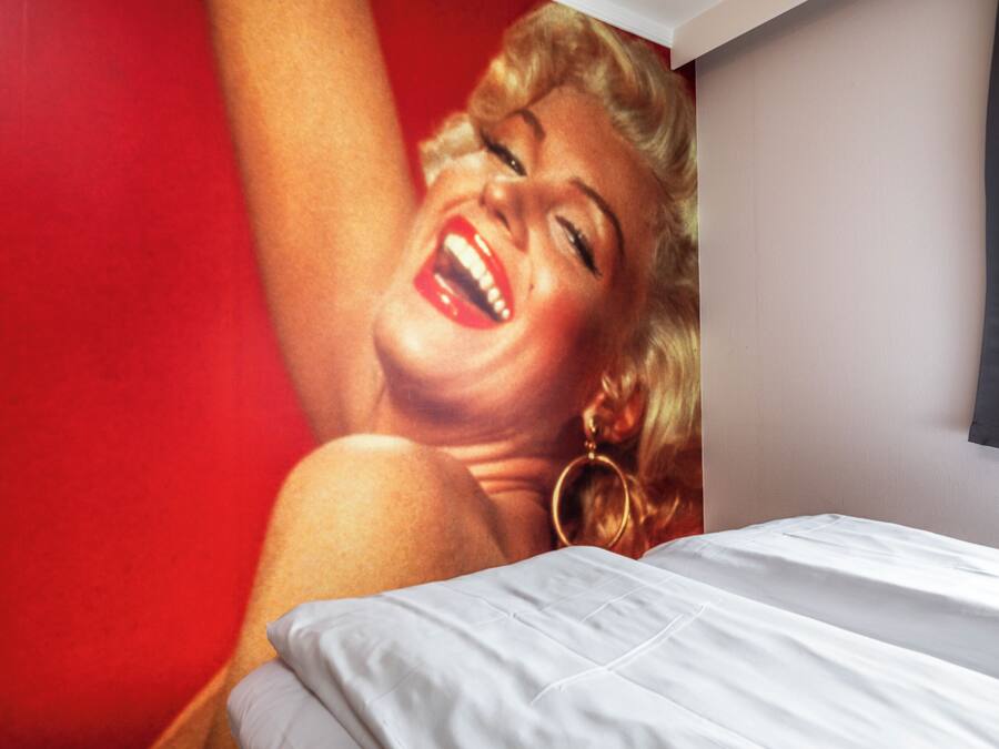 A bed with white bedding and a red wall in the background.