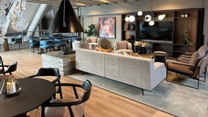 A modern living room with a sofa, chairs, a dining table, and a TV.