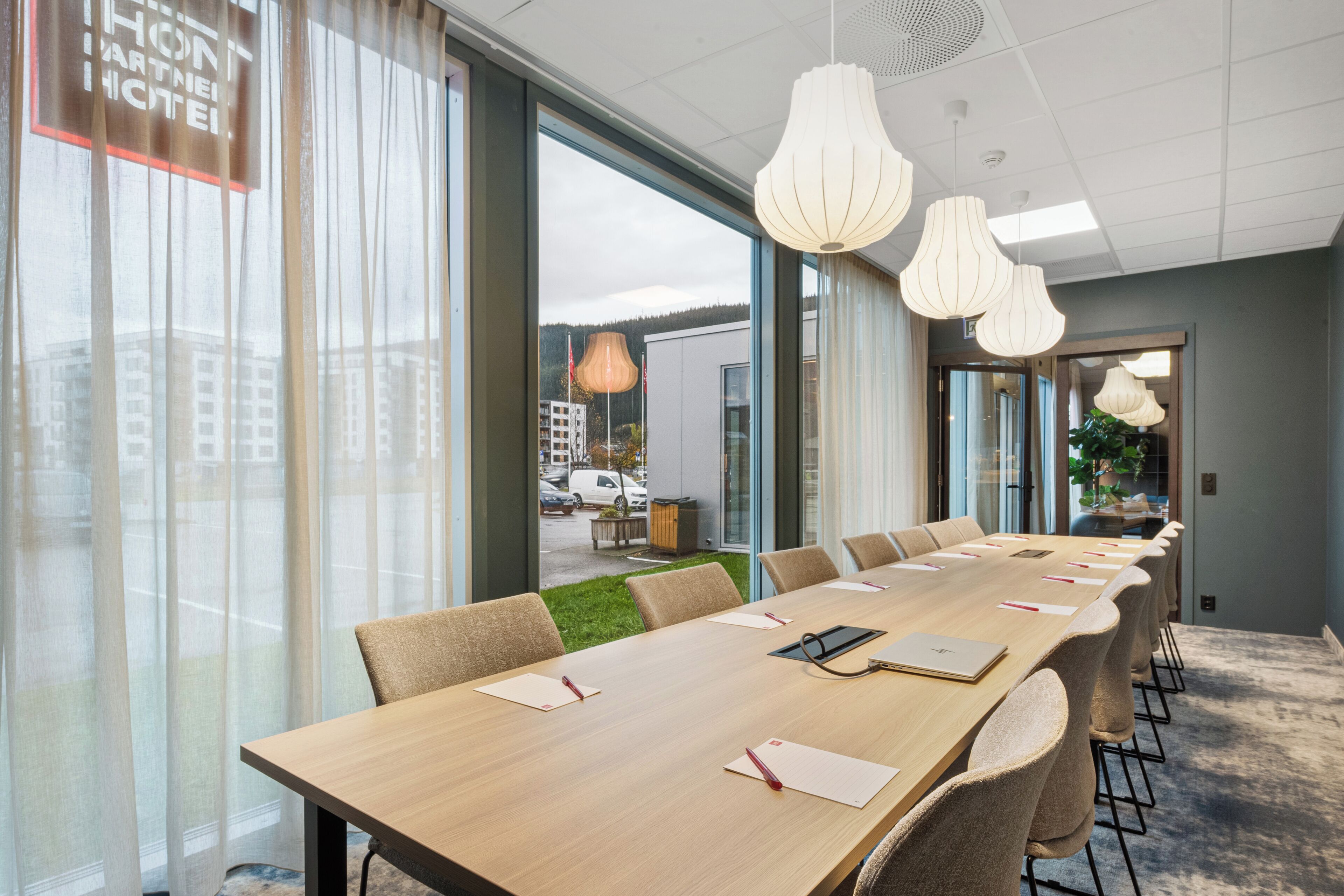 A conference room with a long table, chairs, and a view of the outside.