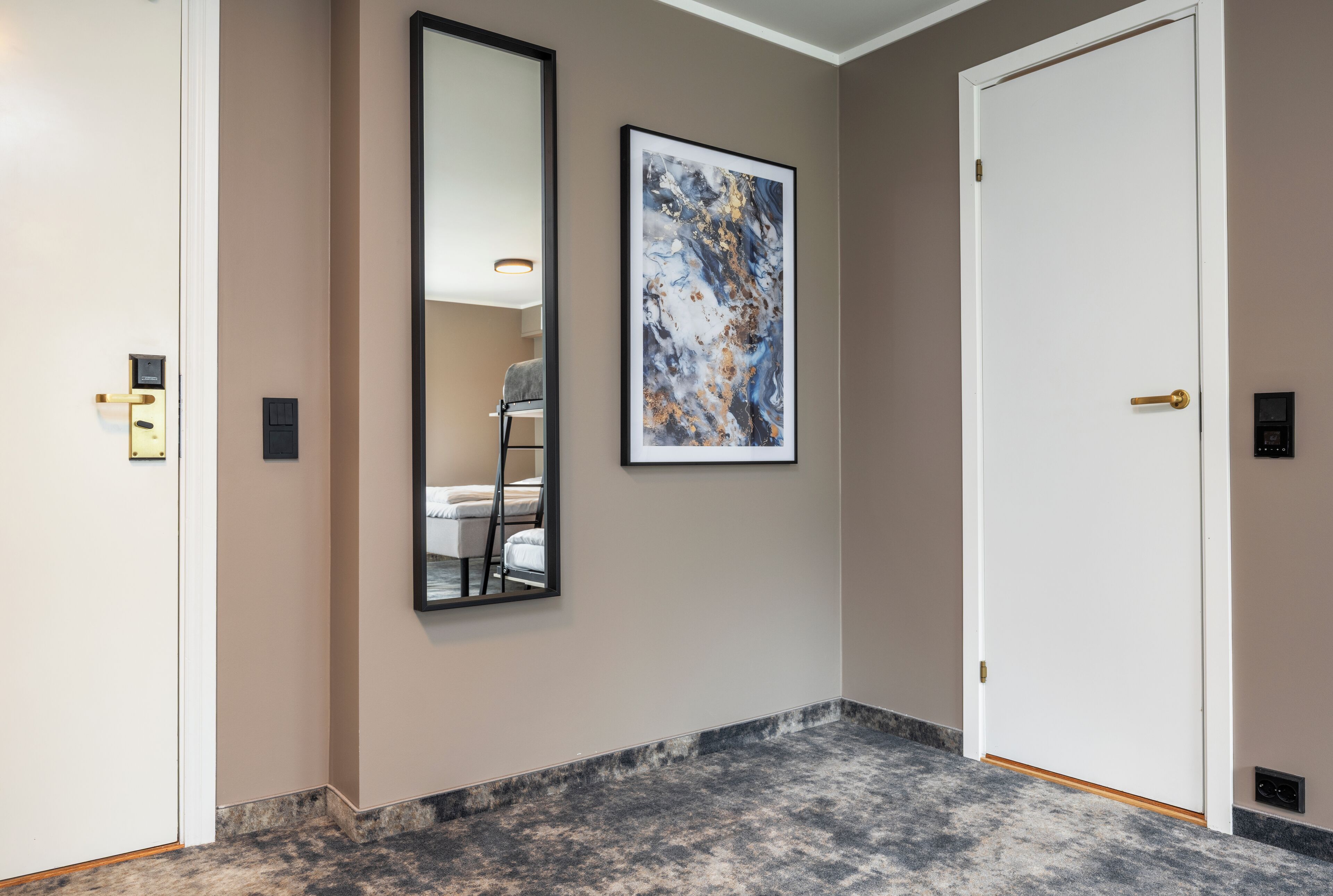 A hallway with a marble floor, a framed abstract painting, a large mirror, and a white door.