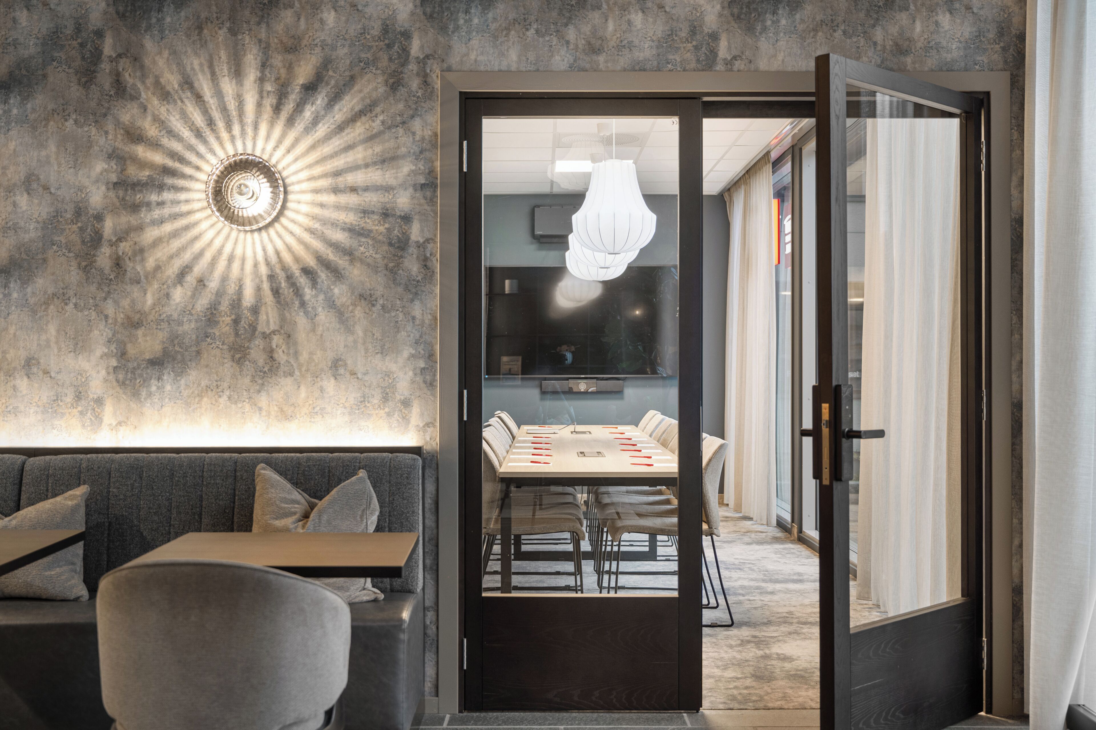 Un interior moderno con zona de comedor, un sofá y una lámpara de pared original.