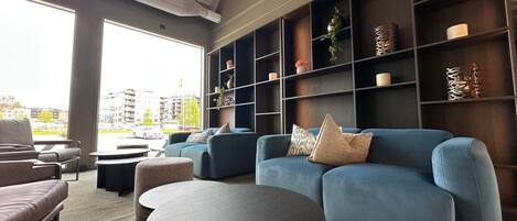 Una sala de estar moderna con un sofá azul, una mesa de centro redonda y una estantería llena de objetos decorativos.