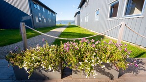 A pathway leading to a building with a view of a lake. There are flower planters along the path.