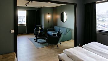 A modern hotel room with a sofa, a small table, a chair, and a bed.
