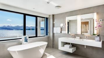 Un baño moderno con una bañera independiente, un espejo grande y un tocador con dos lavamanos.