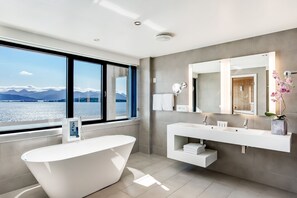 A modern bathroom with a freestanding bathtub, a large mirror, and a vanity with two sinks.