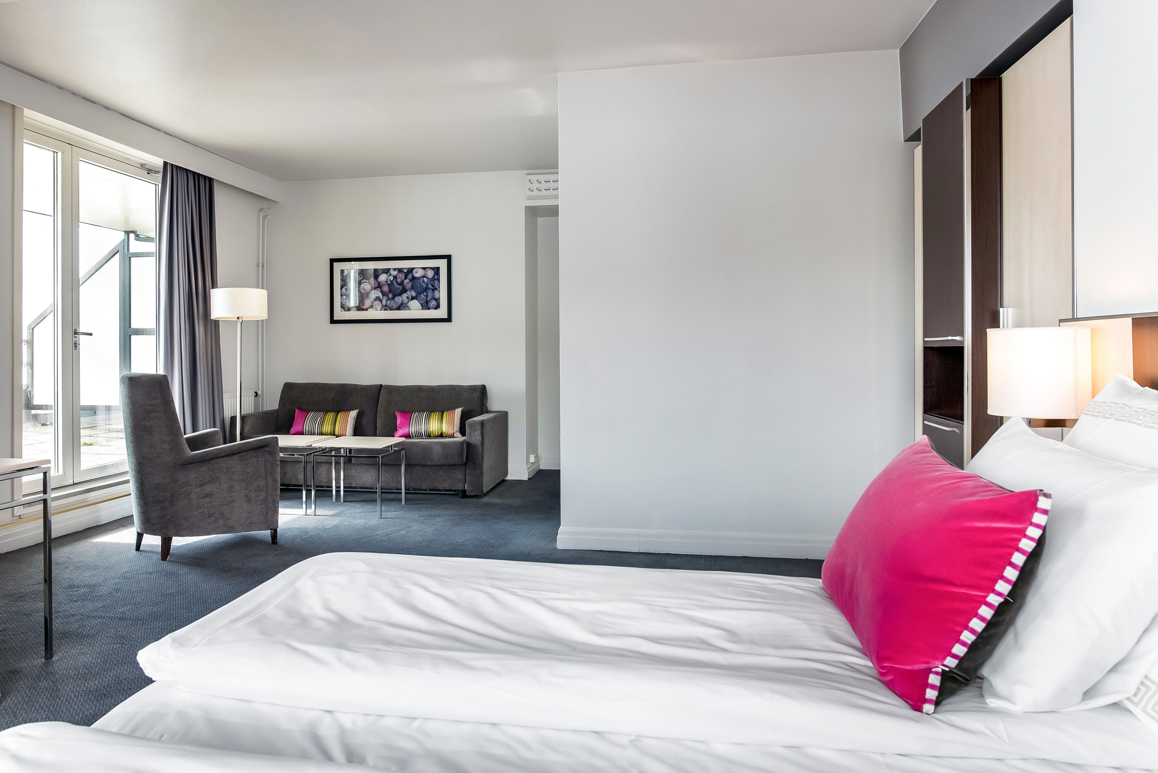A hotel room with a bed, a chair, a sofa, and a desk.