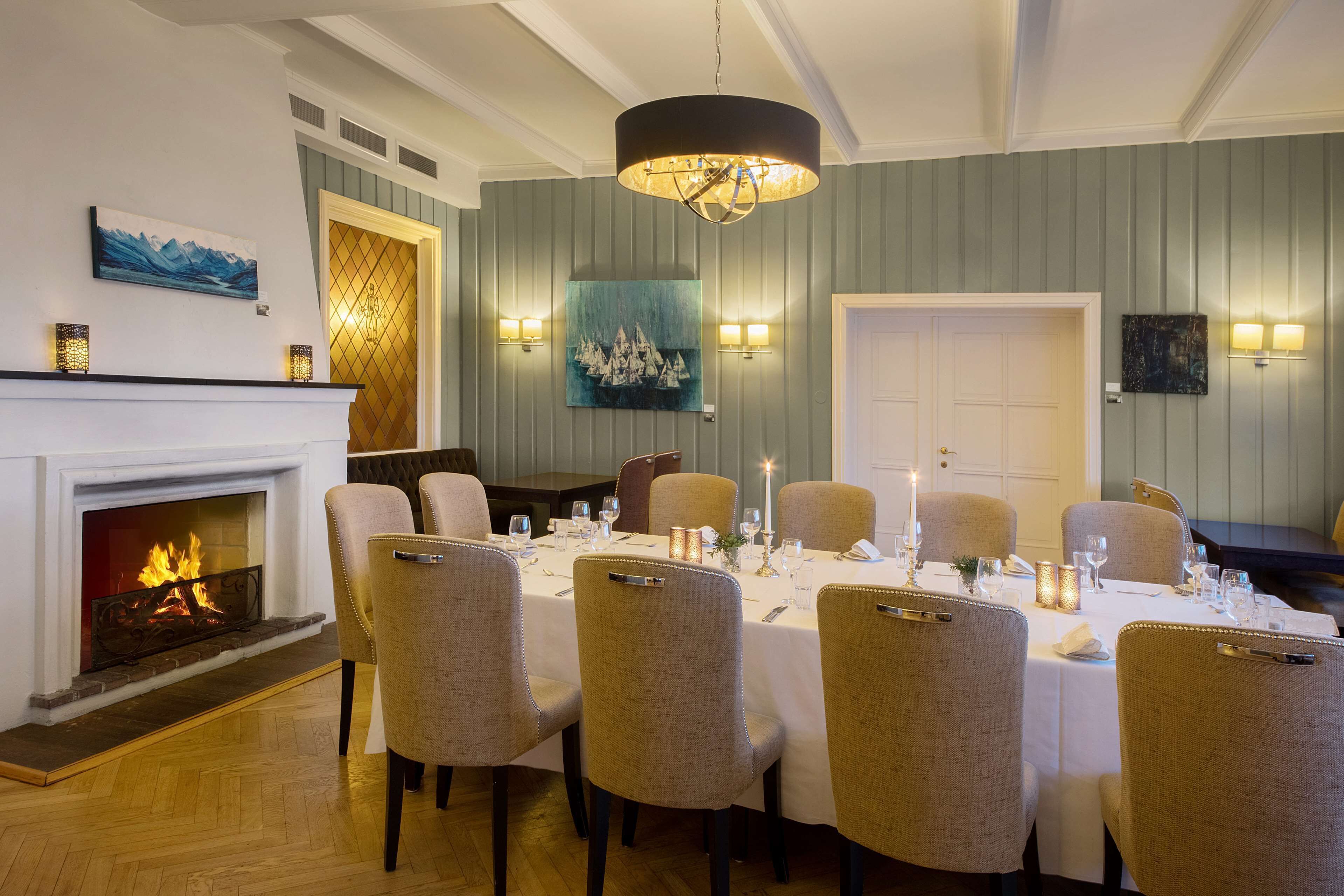A dining area with a fireplace, a chandelier, and a table set for six.