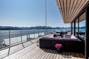 A deck with a sofa, a table, and chairs, overlooking a body of water and mountains. - Scandic Alexandra Molde (Molde)