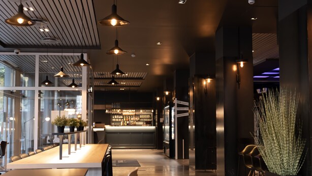 A modern bar area with pendant lighting, a long counter, and seating. - Comfort Hotel Børsparken (Oslo)
