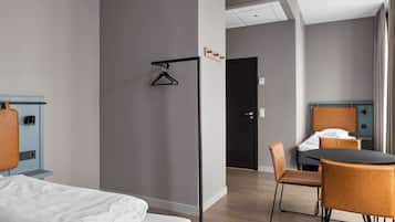 Una camera d'albergo con un letto, una scrivania con una sedia, un tavolo da pranzo con sedie e una porta.