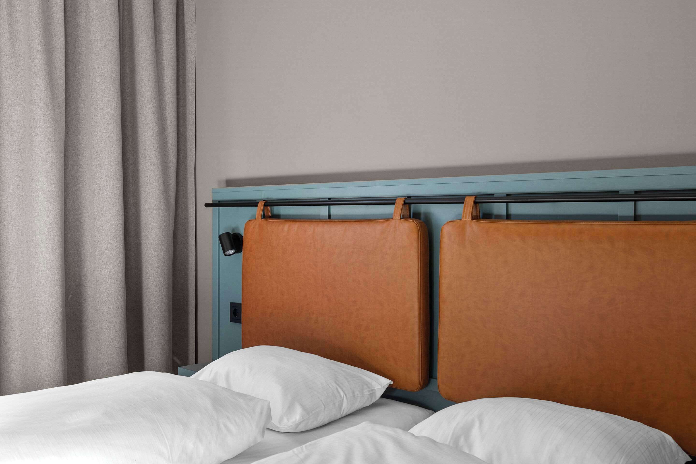 A hotel room with a bed, curtains, and a headboard.