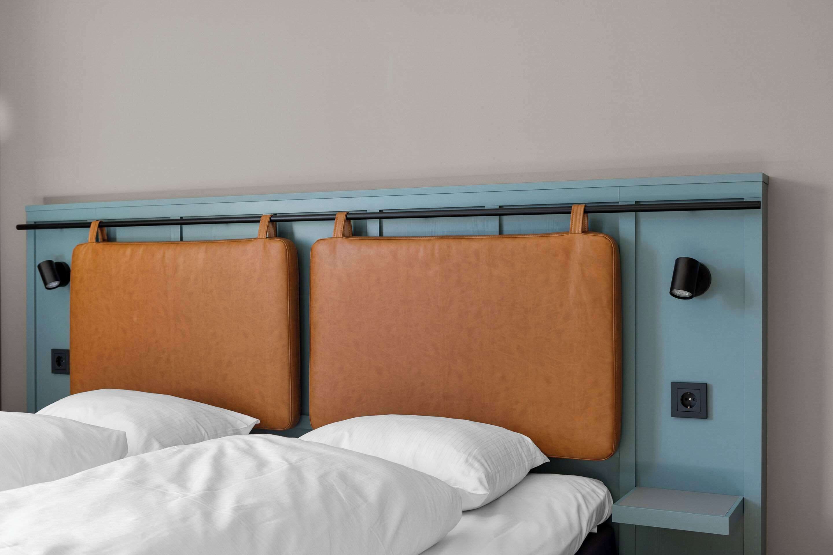 Un lit avec une tête de lit, deux tables de chevet et un luminaire fixé au mur.