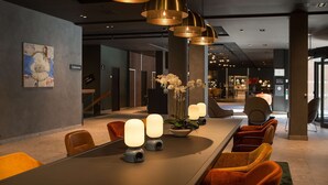 Un vestíbulo de hotel moderno con una larga recepción, asientos cómodos e iluminación ambiental.