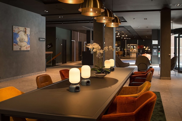 A modern hotel lobby with a long reception desk, comfortable seating, and ambient lighting.