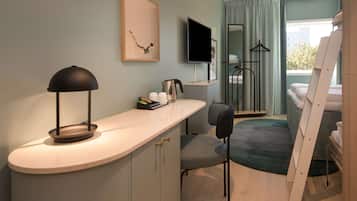 Una habitación de hotel moderna con una encimera curva, un escritorio, una silla, una cama, un televisor y una ventana con cortinas.