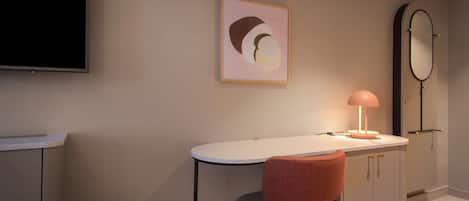A modern room with a white desk, a red chair, a framed artwork, a mirror, and a television.