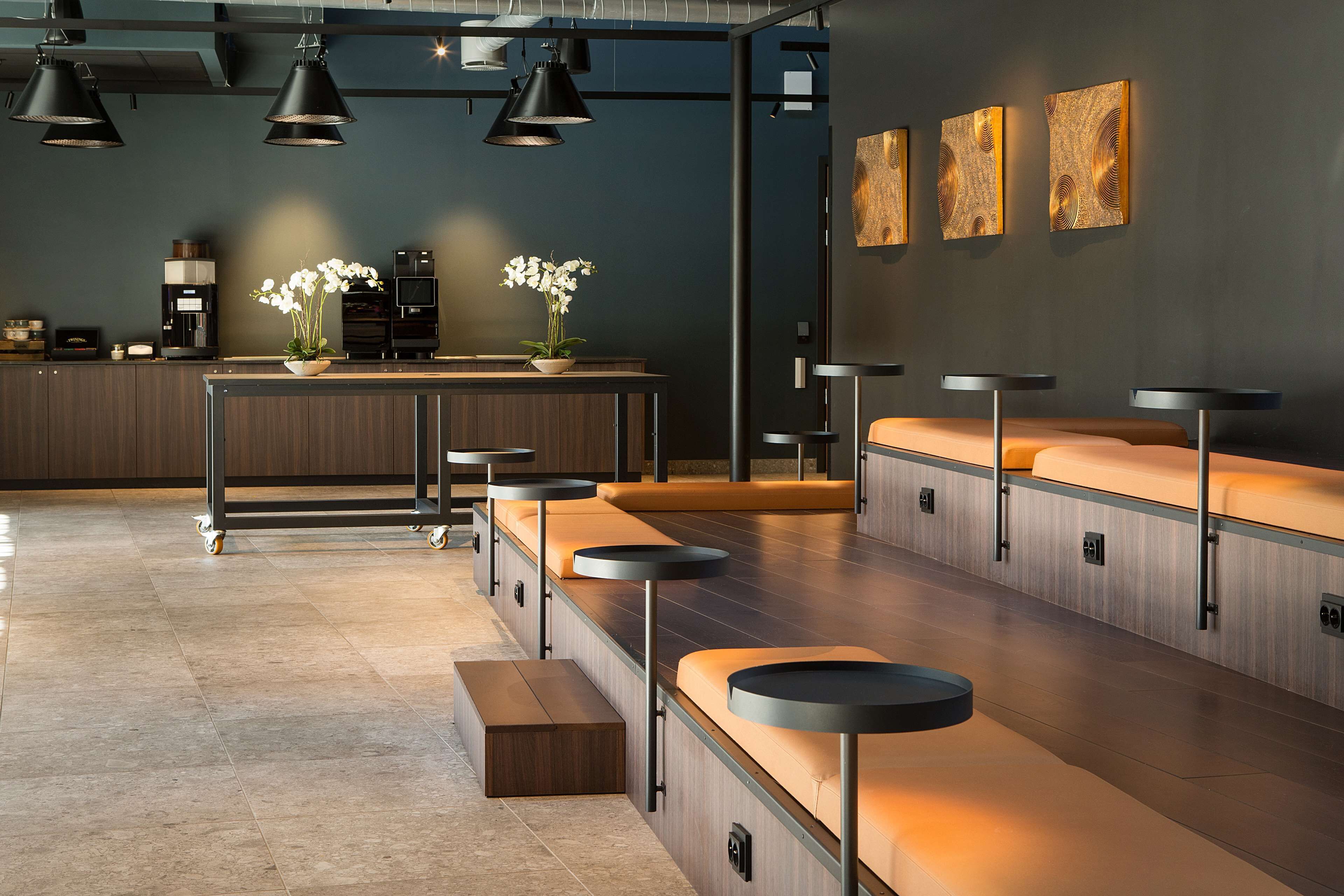 A modern bar area with a long counter, stools, and pendant lighting.