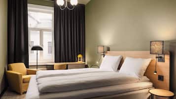 A hotel room with a large bed, a desk, a chair, and two bedside lamps.