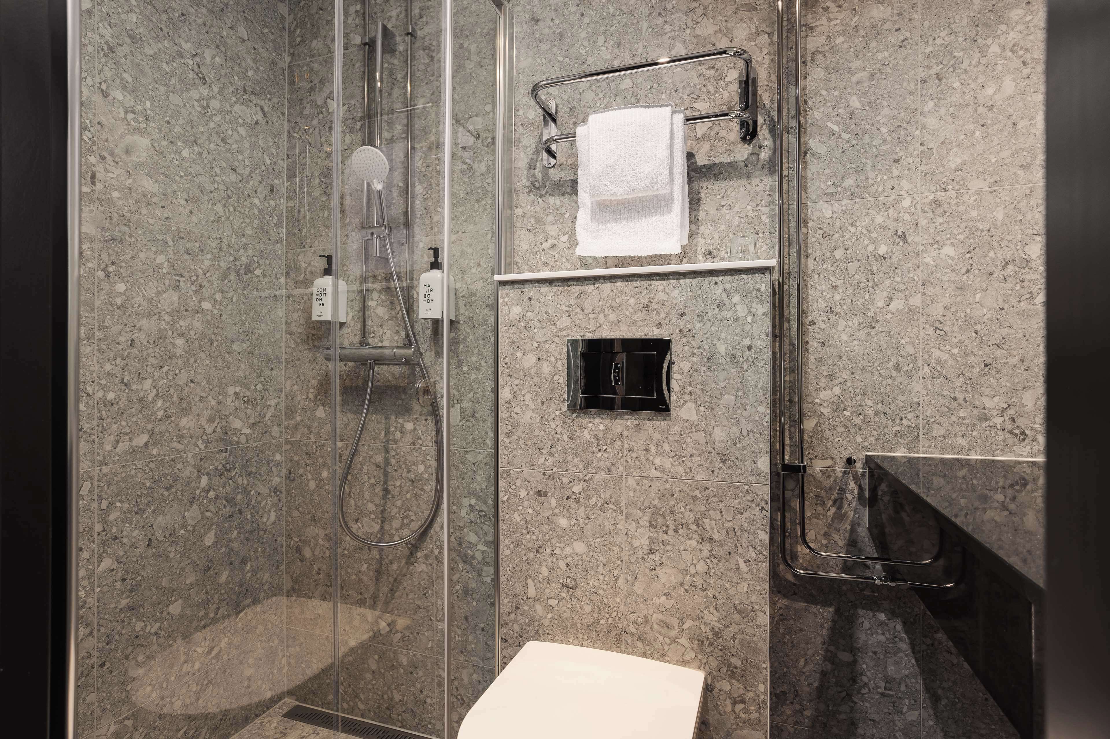 A modern bathroom with a glass-enclosed shower, a white sink, and a towel rack.