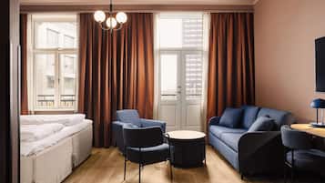 A modern hotel room with a bed, two sofas, a round table, and a TV.