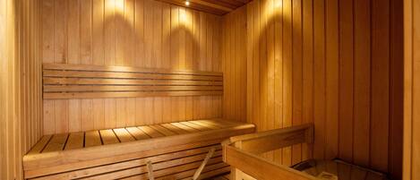 Una sauna de madera con bancos y un cubo de agua.