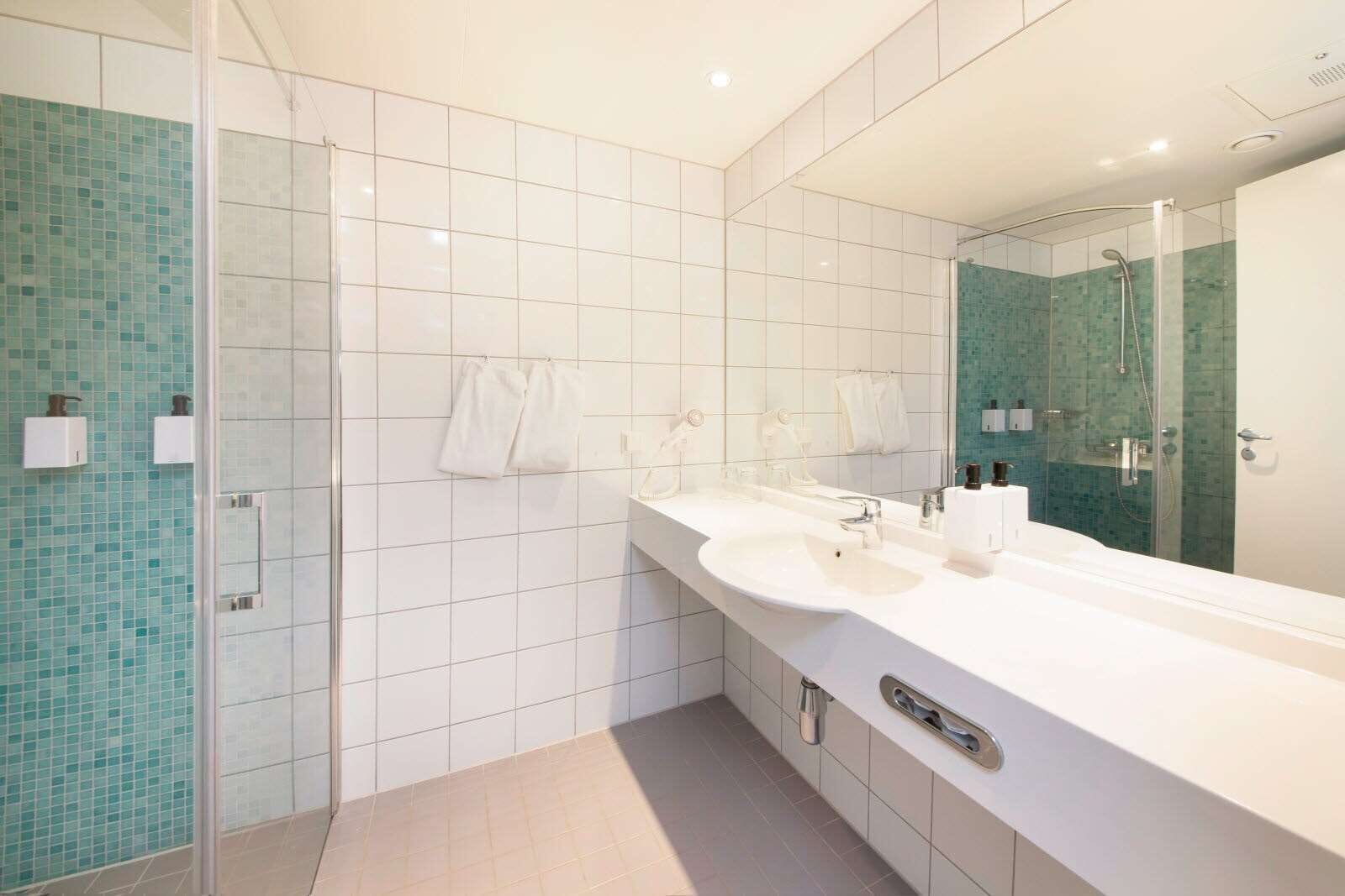 A modern bathroom with a glass-enclosed shower, two sinks, and a large mirror.