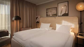 A hotel room with a large bed, a chair, a desk, and a lamp.