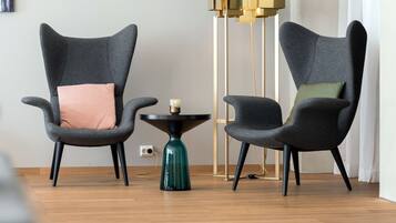 A modern living room with two grey armchairs, a small round table, and a tall floor lamp.